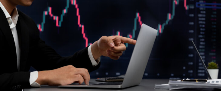 Stock trading investor finger pointing on dynamic financial data graph on monitor. Businessman or broker with analytic thinking analyzing data for stock market exchange trading company. Trailblazing