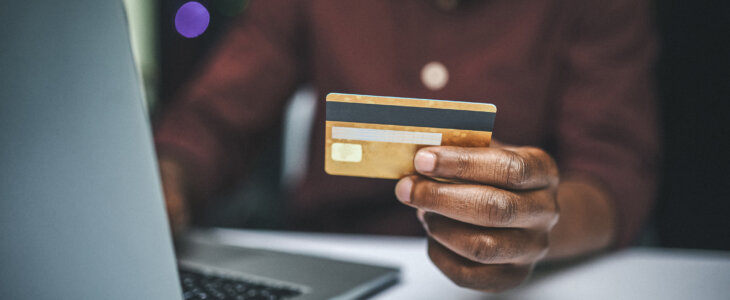 A man holds a credit card and looks at the computer